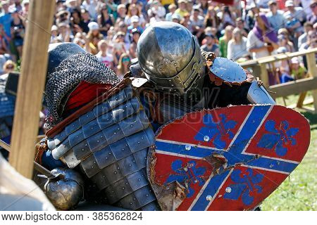 Knight Tournament. Medieval Restorers Fight With Swords In Armor At A Knightly Tournament