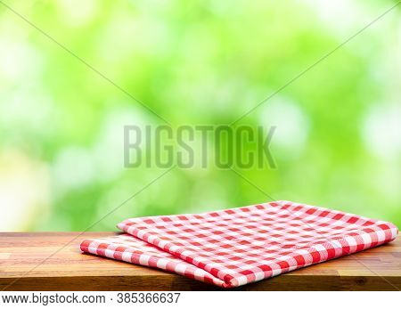 Red Checked Tablecloth On Wood With Blur Green Bokeh Of Tree Background.summer And Picnic Concepts.d