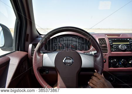 View From Inside A Nissan Car On A Part Of Dashboard And Blurred Desert Road. Steering Wheel. Muscat