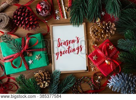 Season's Greetings Text On Cards With Gift Box Present And Ornament Element On Wood Table Background