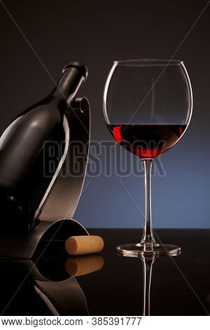 Elegant photo of a glass of red wine with bottle in background.