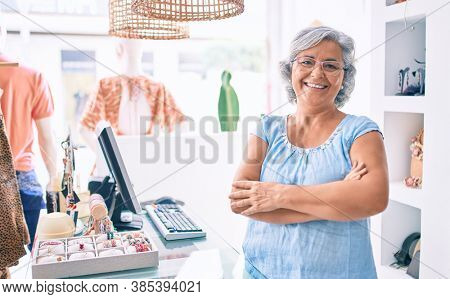 Middle age shop assistance woman working at the counter of retail shop smiling happy