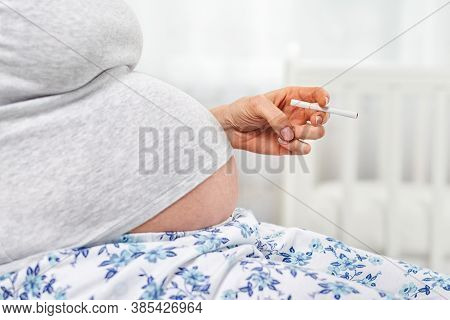 A Pregnant Woman With A Cigarette In Her Hands. Hand With A Cigarette And Stomach Close-up. The Conc