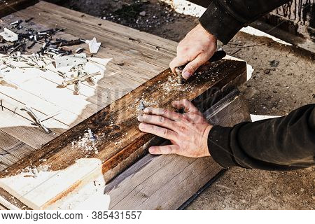 Male Hands Screw A Bolt With A Screwdriver Into A Wooden Board.