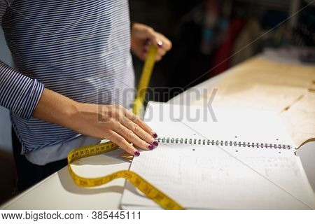 Close-up Of A Seamstresss Hand With A Centimeter. Measures The Cut Line Of The Fabric By Blanks. Tai