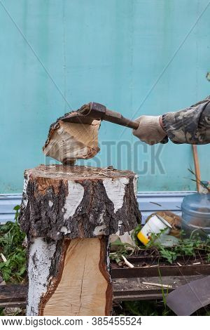 A Log Of Wood Chopped Into An Ax, Smashed Against A Deck By A Man's Hand In Fabric Gloves. Household