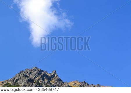 The Top Of The Rock Against The Blue Sky Connects With The Cloud