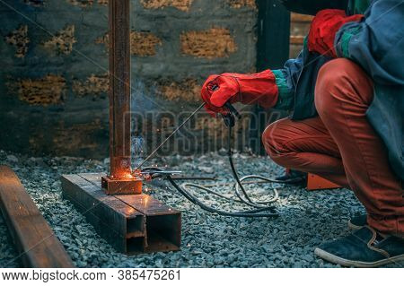 Welder Welds A Metal Pipe With Electric Welding, Holds An Electrode In His Hands
