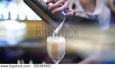 Holding Metal Cup, Pouring Cocktail Into A Glass, Background Of Bartender. Making Cocktail In Night 