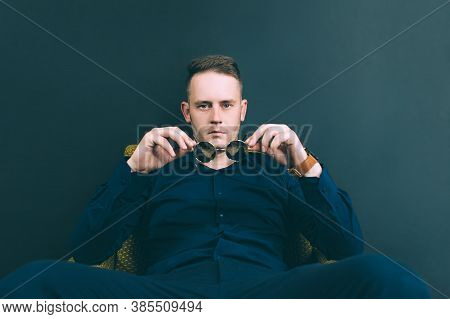 Businessman, Wearing Mirrored Glasses, Sits In An Armchair In The Studio, Looks Through, Glasses. On