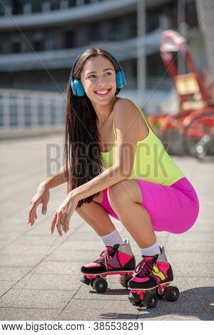 Girl In Roller-skates Sitting On Her Hunkers And Smiling