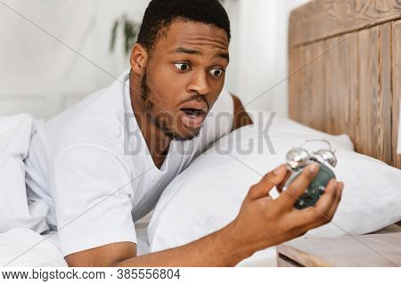 Oversleeping. Overslept African American Man Looking In Shock At Broken Alarm Clock Waking Up In The