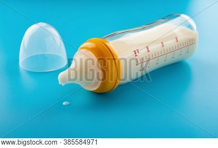 Glass Baby Bottle With Powdered Milk On Blue Background