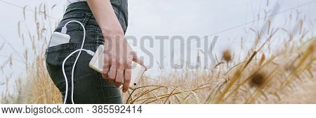Panoramic Web Banner Power Bank In The Back Pocket Of A Girl In A Yellow Field Charges The Phone