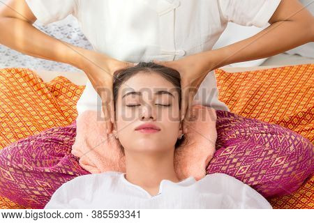 Thai Masseuse Doing Massage For Woman In Spa Salon. Asian Beautiful Woman Getting Thai Herbal Massag