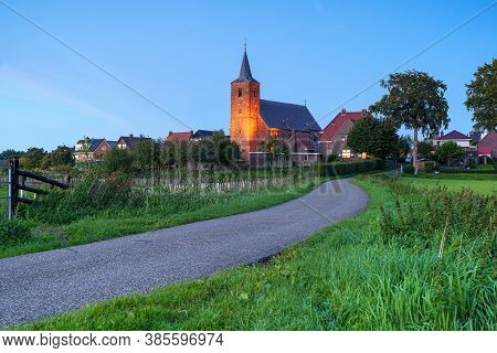 Medieval Church In The Floodplains On A Dike Of A Dutch River Landscape
