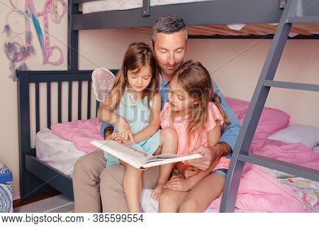 Home Education Homeschooling. Dad Reading Book To Daughters Girls In Bedroom. Family Father And Chil