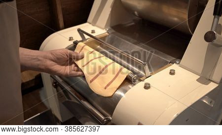 Using Pasta Machine With Dough For Ravioli Making, Male Hands Holding Dough Through Big Past Roller 