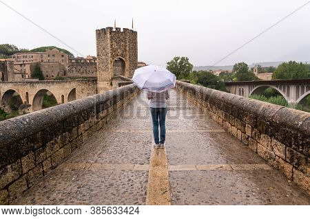 Woman With Umbrella In The Rain On A Bridge In A Medieval Village