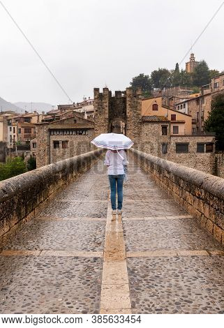 Woman With Umbrella In The Rain On A Bridge In A Medieval Village