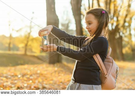 Hourglass And Autumn Dry Leaves. Withering Time Is Autumn.