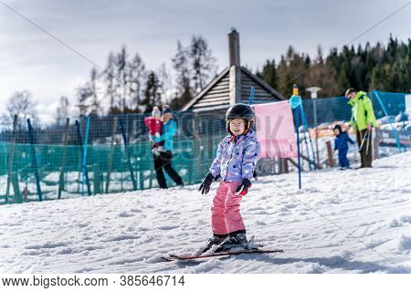 Young Happy Skier Girl Learning How To Ski On The Green Ski Zone. Young Skier Having Fun On Ski Slop
