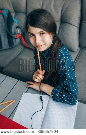 Smiling Little Schoolgirl Doing Her Homework In Front Of A Laptop. Distance Learning.
