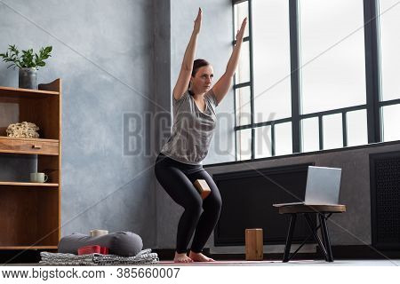 Caucasian Woman Doing Utkatasana, Chair Pose Using Block At Home