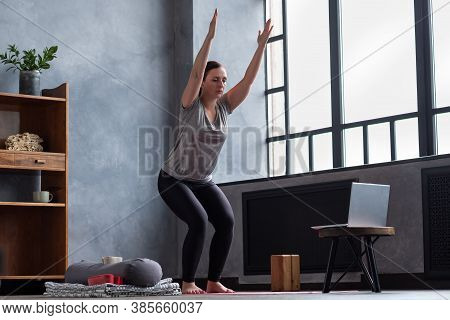 Caucasian Woman Doing Utkatasana, Chair Pose Using Block At Home