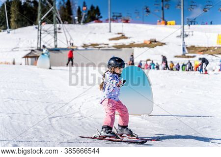 Young Happy Skier Girl Learning How To Ski On The Green Ski Zone. Young Skier Having Fun On Ski Slop