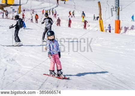 Young Happy Skier Girl Learning How To Ski On The Green Ski Zone. Young Skier Having Fun On Ski Slop