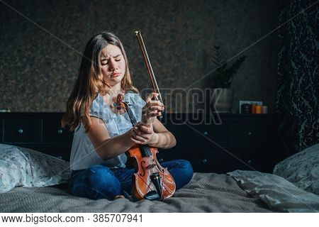 A Young Brunette Girl Injured Her Wrist While Playing The Violin. A Girl Sits On A Bed In Her Room A