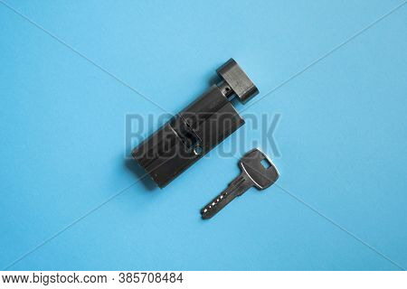 A Door Lock Cylinder Core With Key On The Blue Background. The Cylinder Of The Lock With Key. Instal