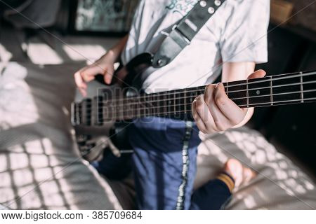 Close Up On The Fingers Of Young Girl Playing Bass Guitar.