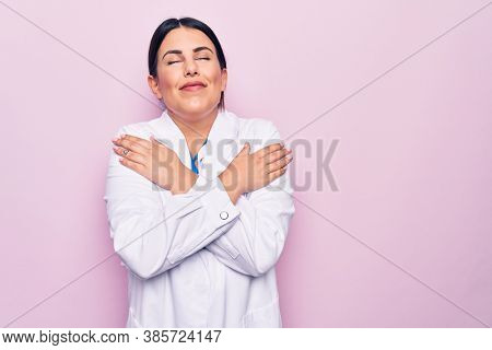 Young beautiful doctor woman wearing stethoscope and id card over isolated pink background hugging oneself happy and positive, smiling confident. Self love and self care