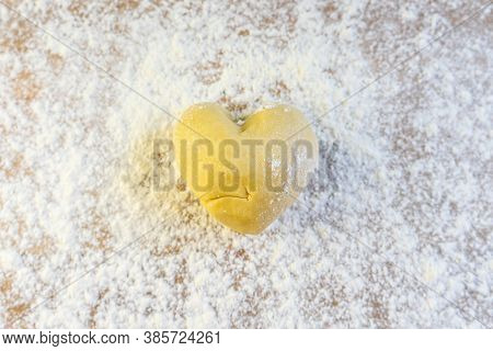 A Piece Of Shortcrust Pastry In The Shape Of A Heart Lies On The Table Sprinkled With Flour.