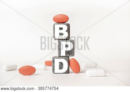 A Group Of White And Red Pills And Cubes With The Word Bpd: Borderline Personality Disorder On Them,