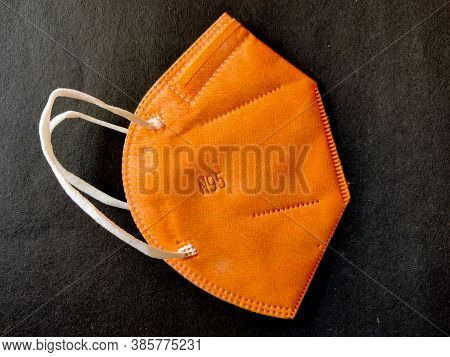 One Orange Color Kn-95 Face Mask Isolated On Black Background. Protection From Coronavirus Or Covid-