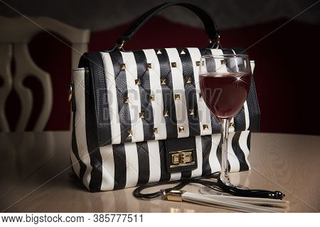 Black And White Bag And Glass Of Red Wine On The Table, Modern Life Style Concept