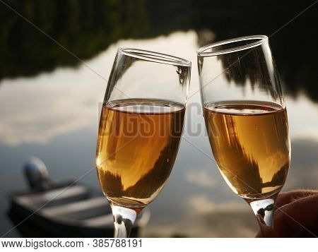 Two Glasses With Rose Champagne Wine In Hands, Romantic Lake As Background