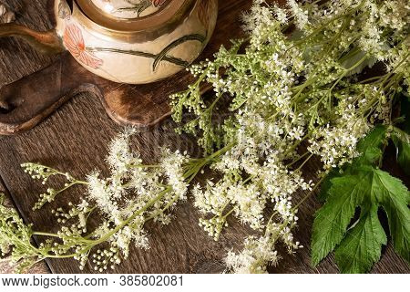 Fresh Meadowsweet Flowers With A Teapot On A Table