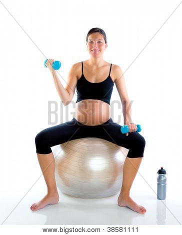 Bella donna incinta in palestra con manubri su palla aerobica