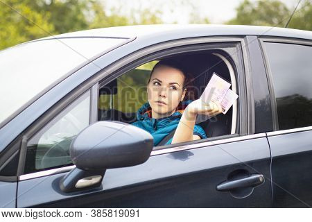 Serious Woman Holding Out Drivers License And Car Documents, Driving Her Car. Traffic Violation Conc