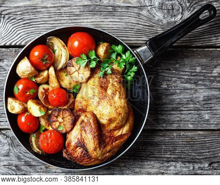 Half Of Roast Chicken In A Skillet With Roasted Potato, Fresh Tomatoes, Peppers And Herbs On A Rusti