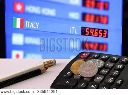 Heap Of Italy Coins On Calculator And Pencil On White Floor With Digital Board Of Currency Exchange 