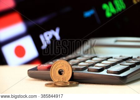 Japanese Five Yen Coins (jpy) On White Floor With Black Calculator And Digital Board Of Currency Exc