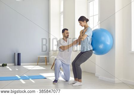 Physiotherapist Helping Young Woman Recover From Back Injury Using Big Soft Ball