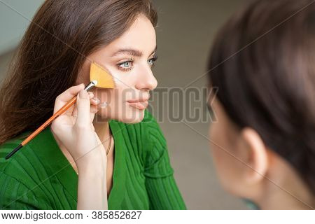 Make Up Artist Applying Professional Make Up Of Tonal Foundation On The Face Of Beautiful Young Cauc