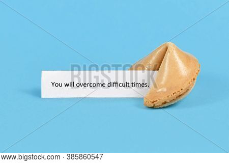 Fortune Cookie With Motivational Text On Paper Saying 'you Will Overcome Difficult Times' On Blue Ba