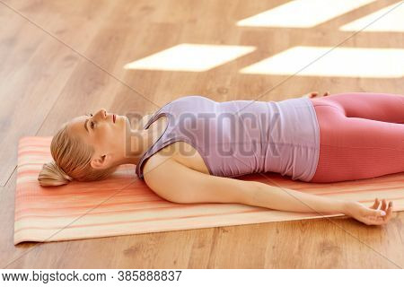 fitness, sport and healthy lifestyle concept - woman doing yoga corpse pose at studio